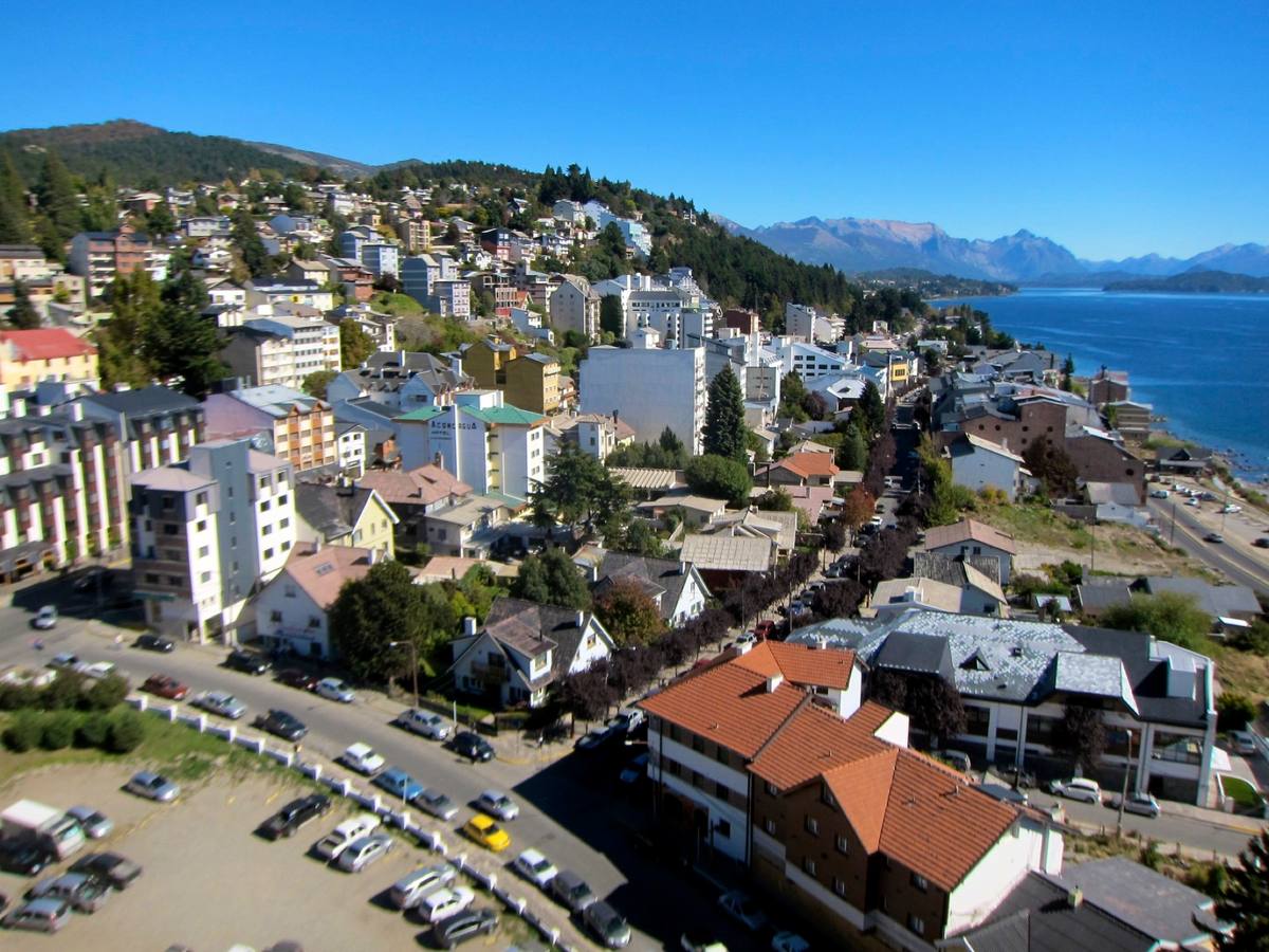 Apartment buildings and hotels cascade down a hillside in San Carlos de Bariloche to the shore of Lake Nahuel Huapi, with the Andes rising beyond the water