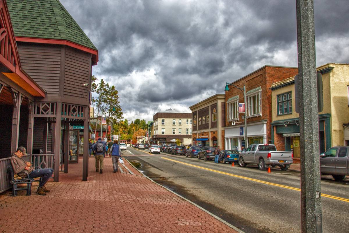 Brick storefronts and pedestrians along Lake Placid's Main Street under a heavy autumn sky
