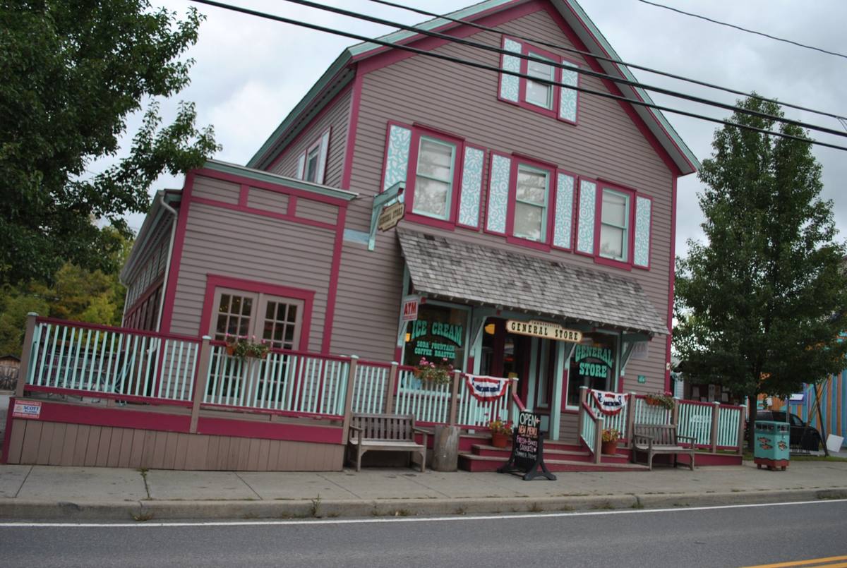 The pink-and-teal painted Victorian storefront of the Tannersville General Store on Main Street, with benches and flower boxes out front